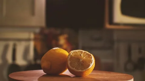 On a cutting board lie two lemons whole and sliced against a kitchen backdrop Stock Footage 160459299