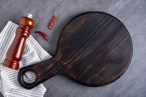 Cutting board or steak serving board with linen napkin, pepper pods and spice Stock Photos