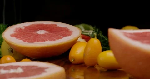Cutting board with sliced grapefruit and falling kumquat. Stock Footage 125599883
