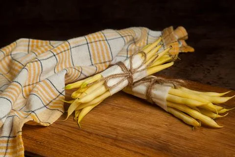 Cutting board with two bunch of flat runner bean pods heap and yellow kitch.. Stock Photos