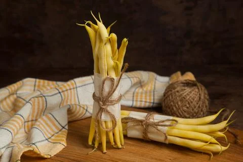 Cutting board with two bunch of flat runner bean pods heap and yellow kitch.. Stock Photos