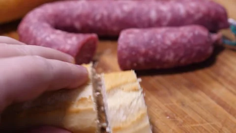 Cutting Bread with Sausages in Background Action Sequence 스톡 동영상 330693592