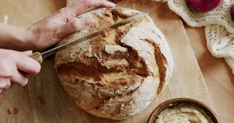 Cutting bread on a wooden table 4K. Video stock 221570437