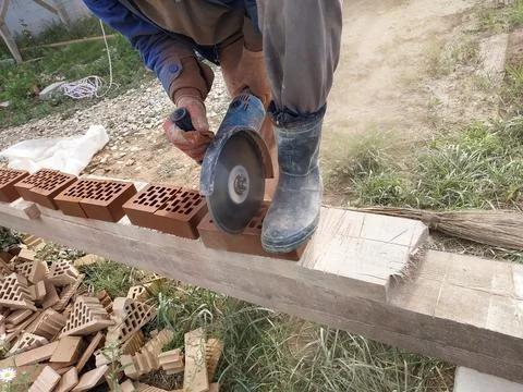 Cutting bricks with an angle grinder in a rural yard. 스톡 사진