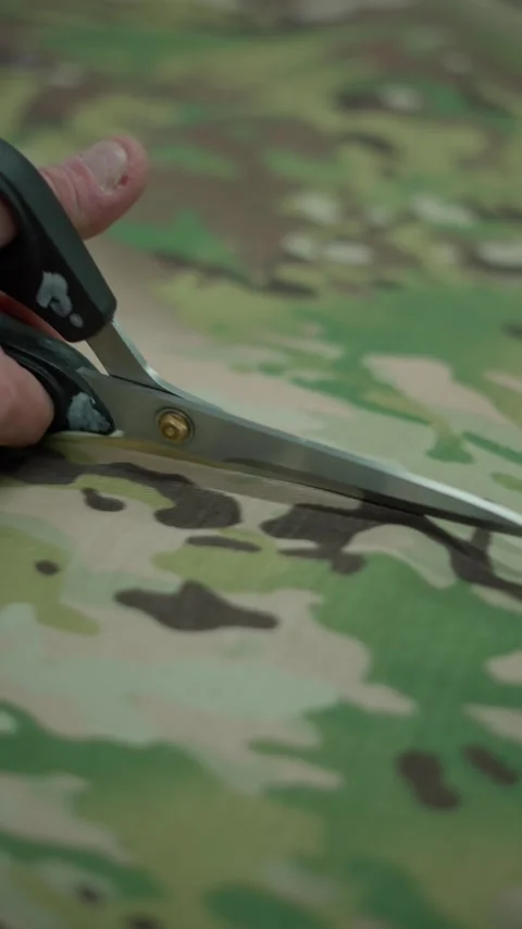 Cutting camouflage fabric with scissors. Tailoring concept. Stock Footage 290507909