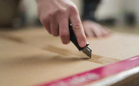 Cutting Cardboard Box on a Flat Surface With a Knife Stock Photos