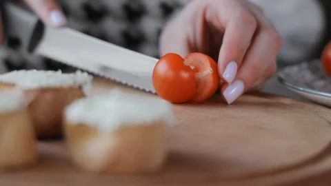 Cutting a cherry tomato, Close-up of hands slicing a cherry tomato on a wooden Stock Footage 300883775