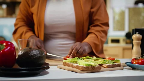 Cutting cherry tomatoes, avocado on toast, black woman chef Stock Footage 333611336
