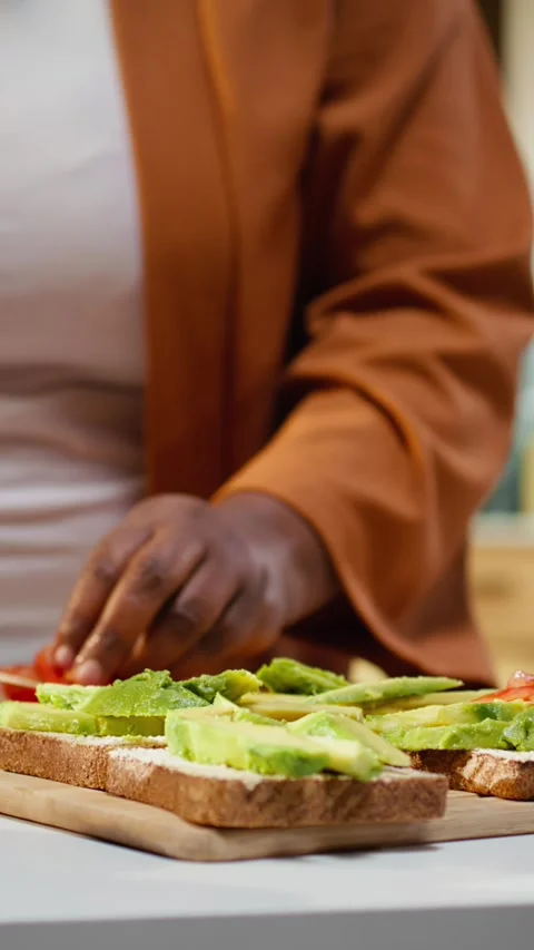 Cutting cherry tomatoes, avocado on toast, black woman chef Stock Footage 333616369
