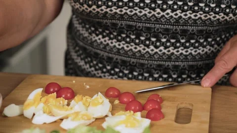 Cutting cherry tomatoes into halves for Caesar salad preparation. Dividing small Stock Footage 316044547
