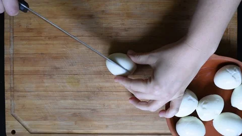 Cutting chicken eggs with a knife into small cubes on a wooden table Stock-Footage 96025279