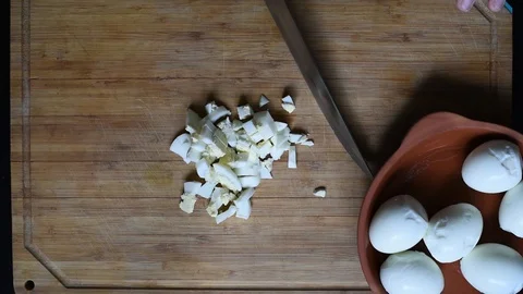 Cutting chicken eggs with a knife into small cubes on a wooden table Video stock 96058437