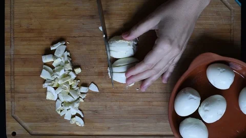 Cutting chicken eggs with a knife into small cubes on a wooden table Stock-Footage 96058566