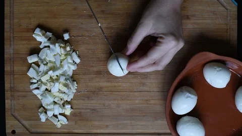 Cutting chicken eggs with a knife into small cubes on a wooden table Stock Footage 96058588