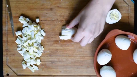Cutting chicken eggs with a knife into small cubes on a wooden table Video stock 96188307