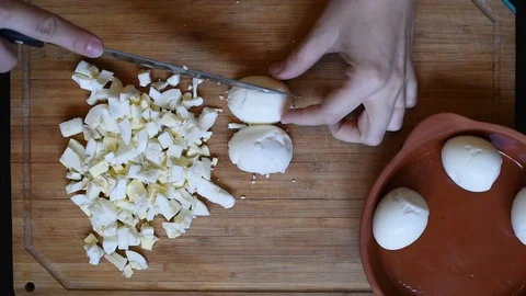 Cutting chicken eggs with a knife into small cubes on a wooden table Stock Footage 96372714