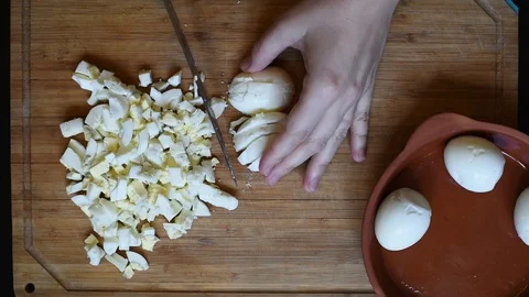 Cutting chicken eggs with a knife into small cubes on a wooden table Stock Footage 96376219