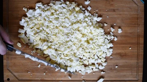 Cutting chicken eggs with a knife into small cubes on a wooden table Stock Footage 96376255