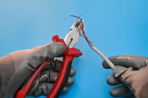 Cutting a computer network wire with wire cutters, blue studio background 写真素材
