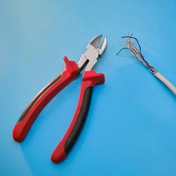 Cutting a computer network wire with wire cutters, blue studio background 写真素材