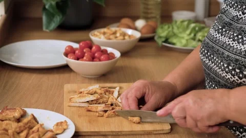 Cutting cooked chicken pieces for preparing Caesar salad. Slicing roasted Stock Footage 333241594