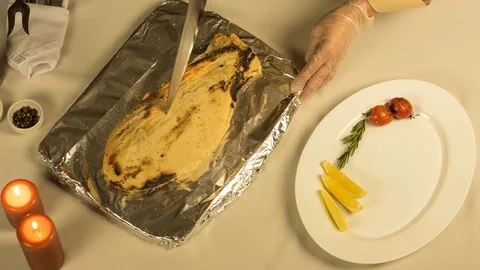 Cutting cooked fish dorado fillets and laying in a plate Stock Footage 69994106