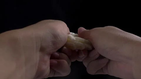 Cutting cracker in half with hand isolated black background Stock Footage 277682438