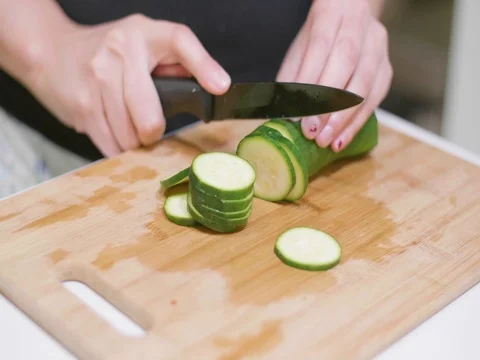 Cutting a cucumber on cutting board Stock Footage