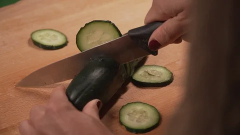 Cutting cucumber with knife on chopping board Stock Footage 128987516