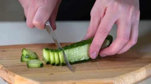 Cutting a cucumber with a knife on a cutting board. A woman cuts a cucumber with Stock Footage 151509814