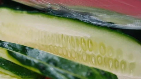 Cutting a cucumber with a knife on a red cutting board in black gloves in 4k Stock Footage 99221301