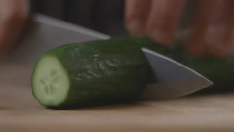 Cutting cucumber into thick chunks with a knife on a chopping board Stock Footage 194478596