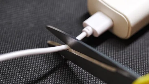 Cutting a damaged charging cable for repair Stock Footage 333684665