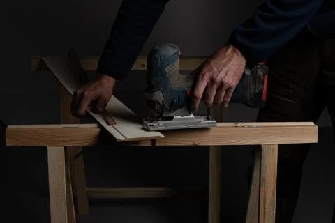 Cutting decorative wall panel board with jigsaw in DIY home renovation Stock-Fotos