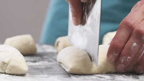 Cutting dough for bread rolls on a table. Stock Footage 154939750