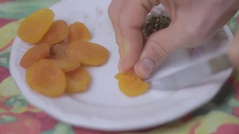 Cutting dried apricots on a plate Stock Footage 75612448