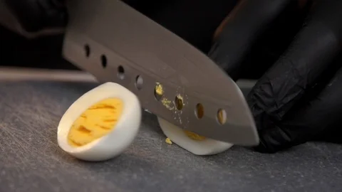 Cutting egg in half on grey plastic cutting board Stock Footage 121364346