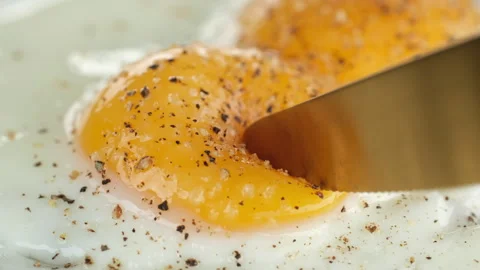 Cutting the egg yolk with a knife, the egg yolk flows out Video stock 245345310