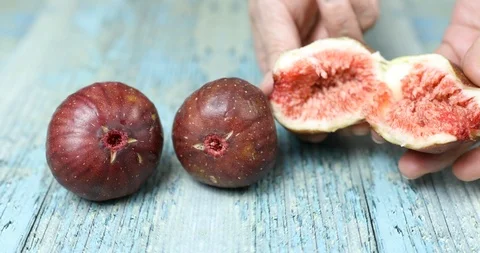 Cutting fig in half with hands on blue wooden table Stock Footage 115930625