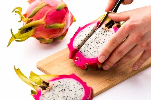 Cutting off a first fruit chip from a pitaya half Stock Photos