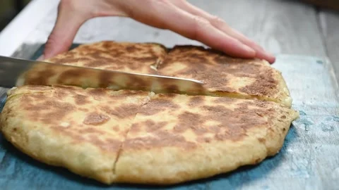 Cutting flat bread with potatoes and cheese on a wooden cutting board. Stock Footage 246860865