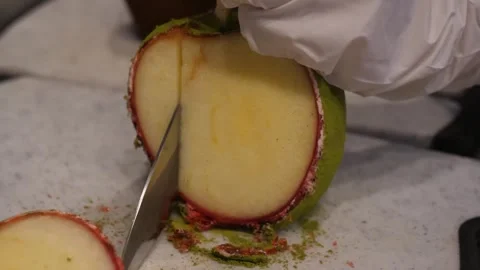 Cutting a Fresh Chamoy and Tajin Covered Apple with a Knife Stock Footage 345292779