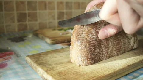 Cutting fresh crusty bread close-up. Knife on kitchen table. Stock Footage 87565950