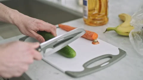Cutting fresh cucumbers on a kitchen cutting board for healthy snacks Stock Footage 310202782