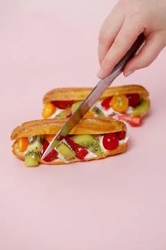 Cutting fresh fruit eclair on pink background for dessert 库存照片