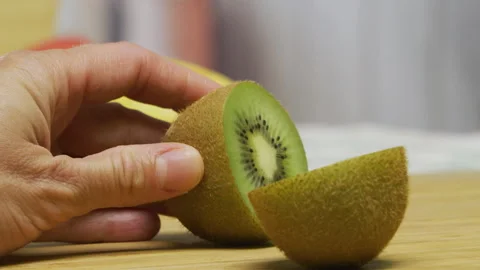 Cutting fresh kiwi in half with large knife - closeup shot Stock Footage 341027608
