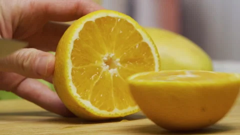 Cutting fresh orange in half with large knife - closeup shot Stock Footage 341184322