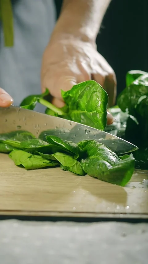 Cutting fresh spinach leaves close up vertical video. preparing healthy meal Stock Footage 274738164