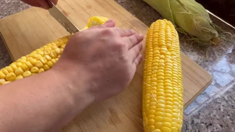 Cutting Fresh Yellow Corn Cobs on a Wooden Cutting Board Stock Footage 345320358