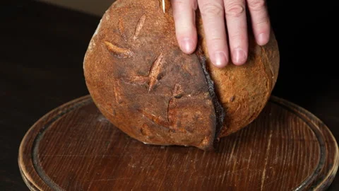 Cutting freshly baked bread in half with a kitchen knife, close up Stock Footage 302162620